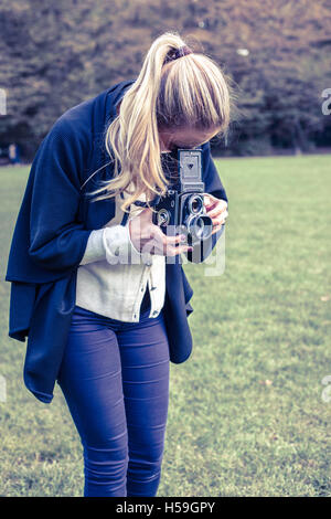 Young woman taking photo avec l'ancien appareil photo classique Banque D'Images