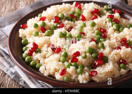 Couscous aux pois verts et grenadier gros plan sur la table. L'horizontale Banque D'Images