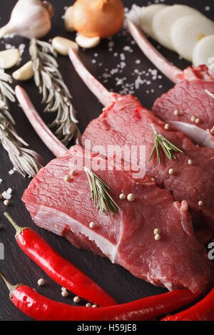 La viande de boeuf cru avec des ingrédients sur un tableau noir ardoise libre verticale. Banque D'Images