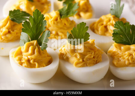 Oeufs farcis à la moutarde et le persil macro sur une plaque horizontale. Banque D'Images