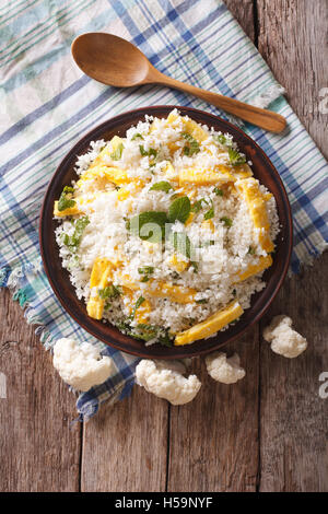 Paleo Nourriture : riz Chou-fleur avec des œufs brouillés et des herbes sur une assiette. vertical Vue de dessus Banque D'Images