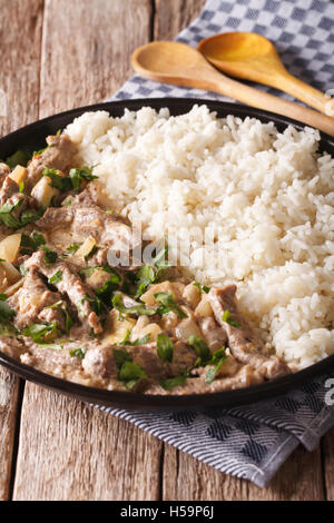 La cuisine russe : boeuf stroganoff avec du riz sur une plaque sur la table. La verticale Banque D'Images