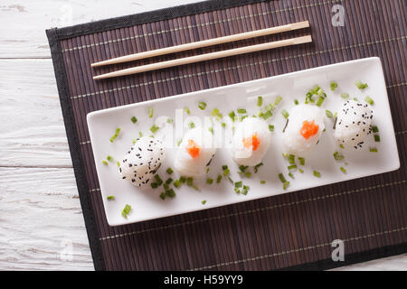 La nourriture japonaise onigiri boules de riz sur une plaque blanche horizontale Vue de dessus. Banque D'Images