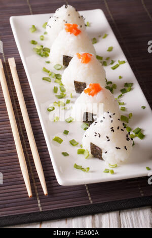 La nourriture japonaise boules de riz onigiri close-up sur une plaque blanche. La verticale Banque D'Images