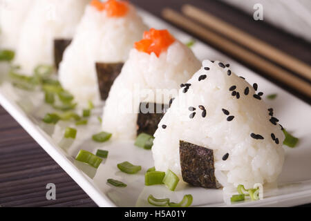 La nourriture japonaise boules de riz onigiri macro sur une assiette blanche horizontale. Banque D'Images