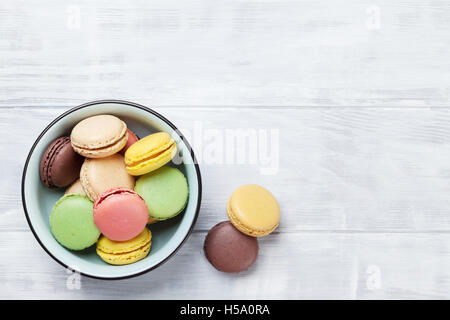 Macarons colorés sur la table en bois. Macarons sucrés. Vue de dessus avec l'exemplaire de l'espace pour votre texte Banque D'Images