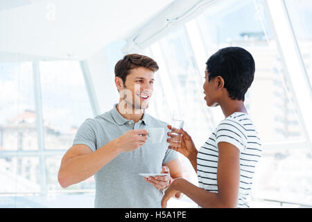 Cheerful young businesspeople standing et discuter bisness plan lors de pause café Banque D'Images