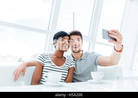 Smiling young couple photo selfies sur smartphone à l'intérieur en restaurant Banque D'Images