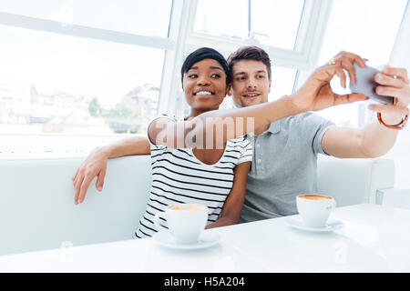 Smiling young couple photo selfies sur smartphone à l'intérieur dans cafe Banque D'Images