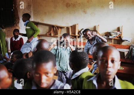 Enfant au centre de l'image est maintenant un appareil photo prendre une photo au matin Assemblée générale dans les régions rurales de l'Ouganda Banque D'Images