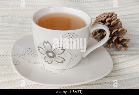 Plateau en Chine tasse et soucoupe, blanc table tricot jeter et pomme de pin. Banque D'Images