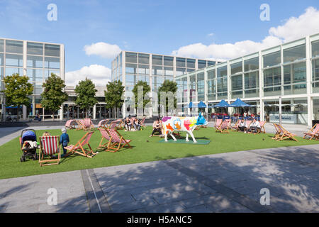 Les gens assis dans des chaises longues dans la cour du plus grand centre commercial de Milton Keynes, MK Centre. Banque D'Images