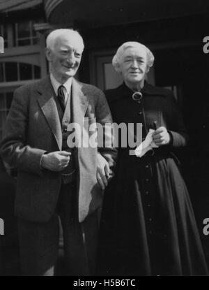 Portrait formel de Lord et Lady Beveridge, pris vers 1957, mettant en valeur leur tenue et leur cadre. L'image les capture debout ensemble dans une pose digne, reflétant le style et le contexte culturel de l'époque. Banque D'Images