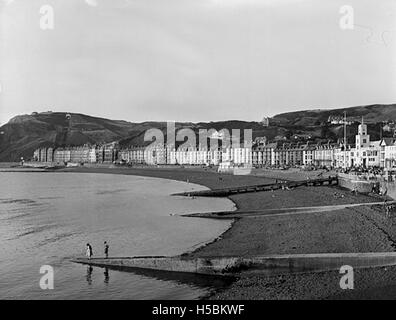 Cette photographie capture une vue panoramique du front de mer d'Aberystwyth, une ville côtière du pays de Galles. L'image met en valeur le port pittoresque de la ville, les plages et la beauté naturelle environnante. Banque D'Images