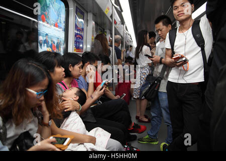 Le peuple chinois de Guangzhou train ride de métro, beaucoup d'entre eux jouer avec les smartphones et une mère est tenant son bébé endormi. Banque D'Images