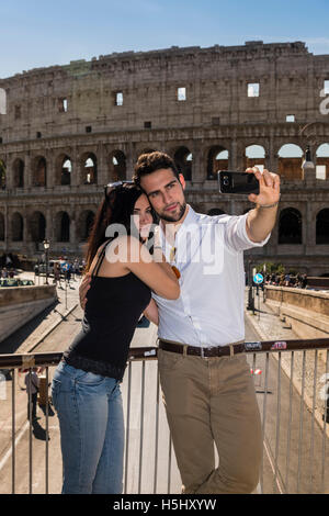 Young caucasian couple prendre une avec un smartphone selfies en face du Colisée, Rome, Latium, Italie Banque D'Images