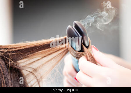 Coiffure L'application d'un fer à repasser tout droit sur une femme Coiffure Banque D'Images