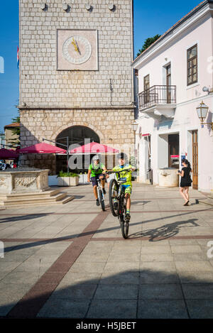 Les garçons faire du vélo à l'ancienne Grande Place, ville de Krk, sur l'île de Krk, Croatie Banque D'Images