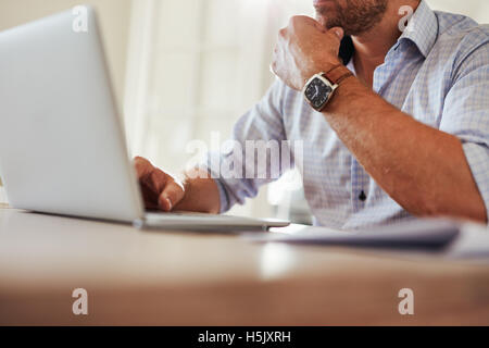 Close up shot of young man sitting at table et travailler sur ordinateur portable. Businessman working from home. Banque D'Images