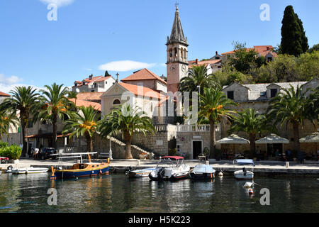 Dans le petit village du port de Supetar, sur l''île de Brac en Croatie, avec quelques petites embarcations et de l'ancienne église. Banque D'Images