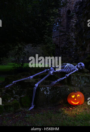 Squelette avec citrouille allumée dans les ruines d'une ancienne abbaye Banque D'Images