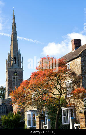 En automne de l'arbre en face de la maison et l'église. Rois Sutton, Nr Banbury, Northamptonshire, Angleterre Banque D'Images