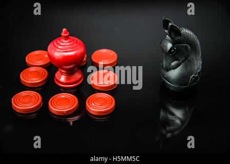 Roi rouge dans le groupe de pions d'échecs défi avec Black Knight Thai chess piece sur fond noir, selective focus Banque D'Images