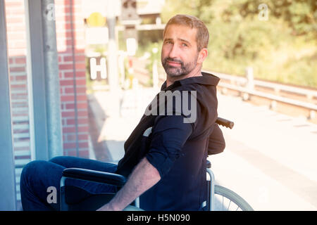 Bel homme dans son 40s assis en fauteuil roulant à gare Banque D'Images