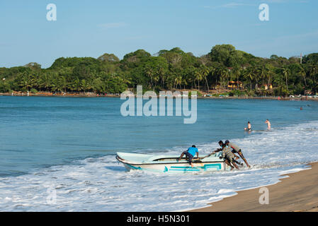 Pousser les pêcheurs d'un bateau en mer, d'Arugam Bay, au Sri Lanka Banque D'Images