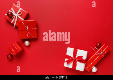 Cadeaux de Noël sur fond rouge. Simple, classique, rouge et blanc cadeaux emballés avec petits nœuds frontière horizontale. Banque D'Images