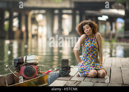 Belle jeune femme asiatique assis sur un quai de la rivière. Banque D'Images