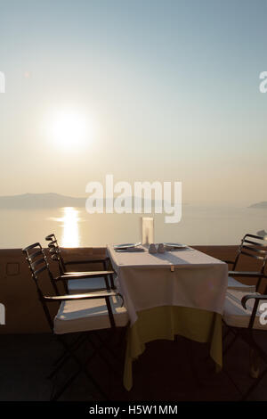 Une table est mise pour le dîner avec le coucher du soleil et d'un bleu profond de la mer et les îles. Banque D'Images