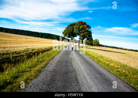 Deux femmes marchant sur une route avec des champs et de ciel bleu. Banque D'Images