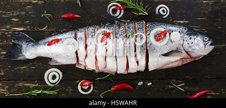 Saumon cru avec des herbes et épices sur sombre conseil rustique. Vue d'en haut. La préparation du poisson pour la cuisson. Aliments sains ou la nutrition alimentation conc Banque D'Images