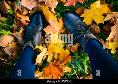 Jeune femme les jambes dans les bottes et les collants colorés tombés en feuilles, rare vue de dessus Banque D'Images