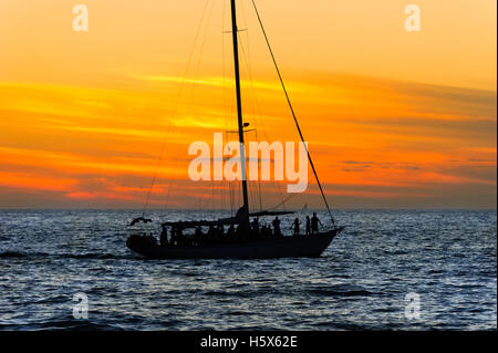 Coucher du soleil voilier parti est un groupe de personnes ayant un bon temps à l'océan au coucher du soleil. Banque D'Images