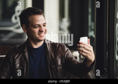 Jeune homme de prendre un café en selfies Banque D'Images