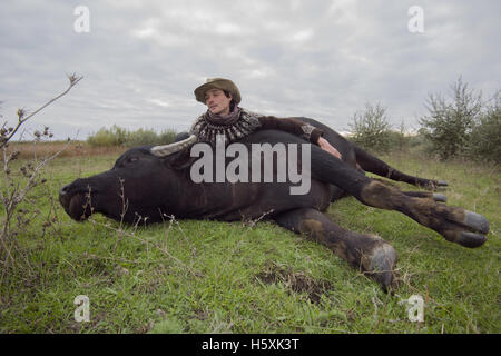 Farmer allongé sur l'herbe à côté de l'eau des Carpates buffalo - Cette sous-espèce sauvage européenne ou le buffle Buffle Banque D'Images