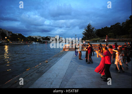 Les gens danser le tango au coucher du soleil dans les jardins de Tino Rossi le long de la Seine à Paris, France Banque D'Images