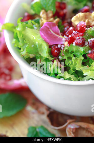 Close up de salade frisée avec grenade, noix, pétales de rose, la menthe poivrée, l'huile d'olive, le vinaigre balsamique et le sel
