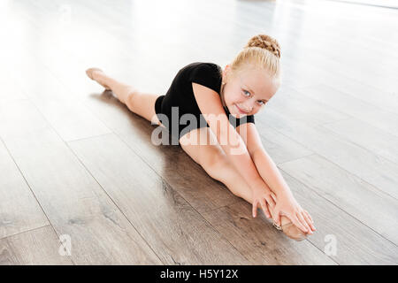 Smiling belle petite fille ballerine faisant ficelle dans le ballet studio Banque D'Images