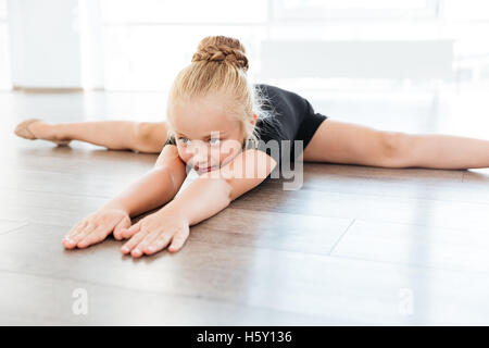 Cute little girl ballerina stretching et faire ficelle dans un studio de danse Banque D'Images