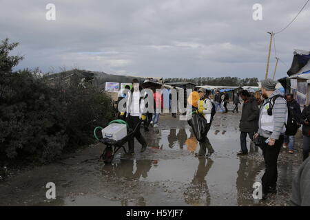 Calais, France. 22 octobre, 2016. Les bénévoles naviguer parmi les flaques dans la jungle, en raison de la pluie havy. La vie quotidienne dans la jungle se poursuit avec quelques jours d'aller à l'expulsion du camp par l'État français. Cependant de plus en plus de gens quittent le camp et le nombre de tentes vides et des huttes augmente. Crédit : Michael Debets/Alamy Live News Banque D'Images