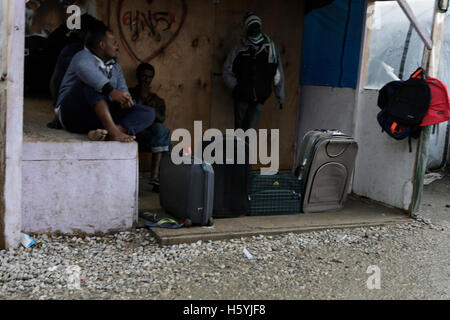 Calais, France. 22 octobre, 2016. Les réfugiés s'asseoir en face d'une hutte avec des valises. La vie quotidienne dans la jungle se poursuit avec quelques jours d'aller à l'expulsion du camp par l'État français. Cependant de plus en plus de gens quittent le camp et le nombre de tentes vides et des huttes augmente. Crédit : Michael Debets/Alamy Live News Banque D'Images