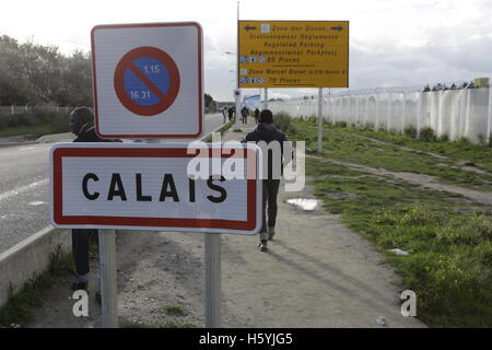 Calais, France. 22 octobre, 2016. Les réfugiés passent devant le panneau pour Calais. La vie quotidienne dans la jungle se poursuit avec quelques jours d'aller à l'expulsion du camp par l'État français. Cependant de plus en plus de gens quittent le camp et le nombre de tentes vides et des huttes augmente. Crédit : Michael Debets/Alamy Live News Banque D'Images