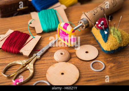 Dans Posamentenknopf avec production d'ébauches de boutons, fils de couleur, des ciseaux et en coussinet sur planche de bois Banque D'Images