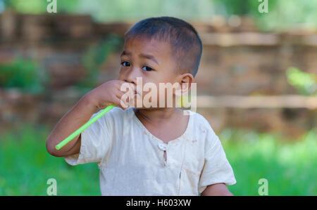 Asian boy avec de la paille dans la bouche,sale avec innocent jeu. Banque D'Images