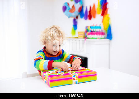 La célébration de l'enfant troisième anniversaire. Petit garçon présente l'ouverture et la tenue des ballons dans la salle décorée. D'anniversaire pour les enfants. Banque D'Images