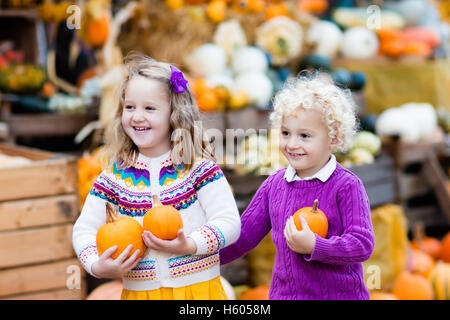 Groupe d'enfants bénéficiant d'harvest festival Célébration à Pumpkin Patch. Kids picking et découper les citrouilles à ferme du pays Banque D'Images