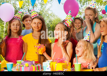 Groupe d'enfants excités félicitant fille d'anniversaire Banque D'Images